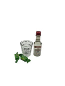 A gift set containing a mini bottle of Smirnoff vodka, a measuring shot glass labeled "ONE SHOT," and two green wrapped sour apple candies.