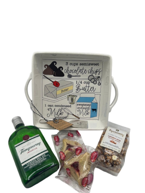 A beautifully designed white ceramic baking dish with an illustrated fudge recipe printed inside. Accompanying the dish is a bottle of Tanqueray London Dry Gin, two Stern’s Hamantaschen cookies, and a bag of Popinsanity Cinnamon Swirl Popcorn, creating a festive Purim gift set.