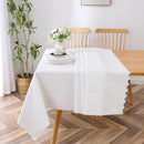 A white lace-patterned tablecloth (70" x 144") draped over a wooden dining table, styled in a modern dining room.