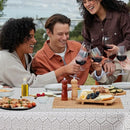 An outdoor dining setting with friends toasting wine glasses over a table covered with the lace tablecloth.
