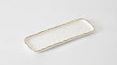 A long, narrow, rectangular white porcelain serving tray with a gold-trimmed, irregular raw edge.