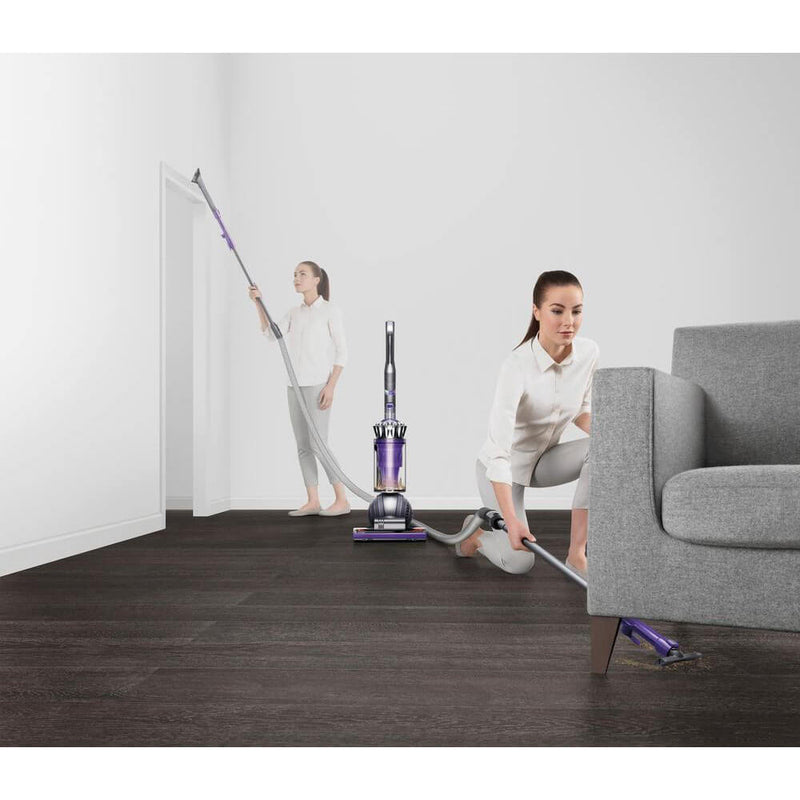 Woman using Dyson's long wand to clean floors and corners.