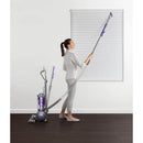 Woman using the vacuum's extension to clean window blinds.