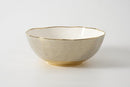 Neutral-toned porcelain bowl with textured exterior and scalloped gold-trimmed rim