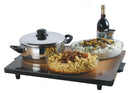 A large, sleek food warming tray holding a stainless steel pot, two glass serving dishes filled with pasta and rice, and a bottle of wine.