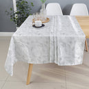 Silver floral tablecloth spread across a dining table with decor