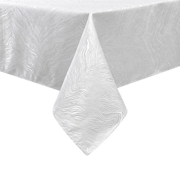 Corner view of a white jacquard tablecloth neatly hanging over the edge of a table