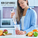 Person using OVENTE cordless immersion blender to blend fruit in a cup