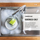 Handwashing a Farberware bamboo cutting board in a sink.