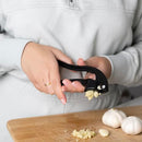 Garlic press squeezing fresh garlic over a wooden cutting board