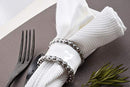 White cloth napkin styled with a silver napkin ring on a place setting