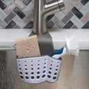 Sponge and brush holder attached to a kitchen faucet, holding a sponge and dish brush over a sink.