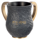 Front view of black and gold washcup with a gold engraving that says 'netilas yadayim' on a white background