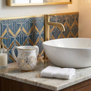 White and gold polymer washcup on a bathroom counter next to a sink