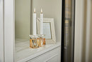 Pair of gold colored crystal candlesticks on a counter with burning candles on them 