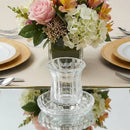 Crystal kiddush cup with a saucer on a table next to a vase with flowers
