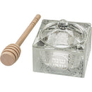 A square, clear crystal honey dish with etched Hebrew designs on its sides and lid, accompanied by a wooden honey dipper.