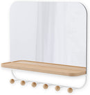 A sleek white wall-mounted organizer mirror with rounded corners, featuring a light wood shelf beneath it. Below the shelf, a white bar extends with several wooden peg hooks.