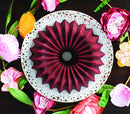 red Bundt cake with defined ridges, sitting on a white plate atop a wooden table,