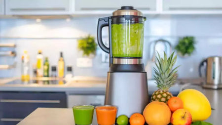 A high-speed countertop blender with a clear jar, filled with fresh fruit and smoothie ingredients, placed on a kitchen counter.