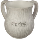A gray, textured polyresin ritual washing cup with two curved handles and a small plaque engraved with Hebrew text.