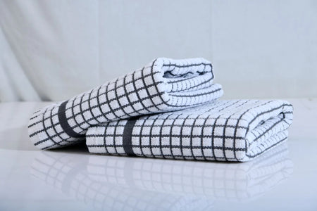 A pair of white and black checkered kitchen towels, neatly folded and placed on a clean surface.