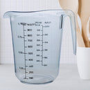 Transparent plastic measuring jug with a 1-liter (1000ml) capacity, featuring black measurement markings for water, sugar, and flour. Ergonomic handle and spout for easy pouring, perfect for baking and cooking.
