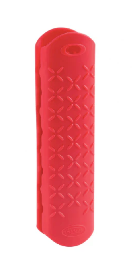 A bright red Trudeau silicone handle grip with a textured surface featuring a repeating "X" pattern. The grip has a curved shape designed to fit over a handle and a small hanging hole at the top. It is shown against a white background.
