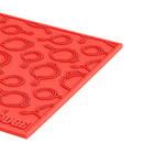 Lodge 7-inch red silicone hot pad and trivet, heat resistant, non-slip, featuring a textured cast iron pan design.