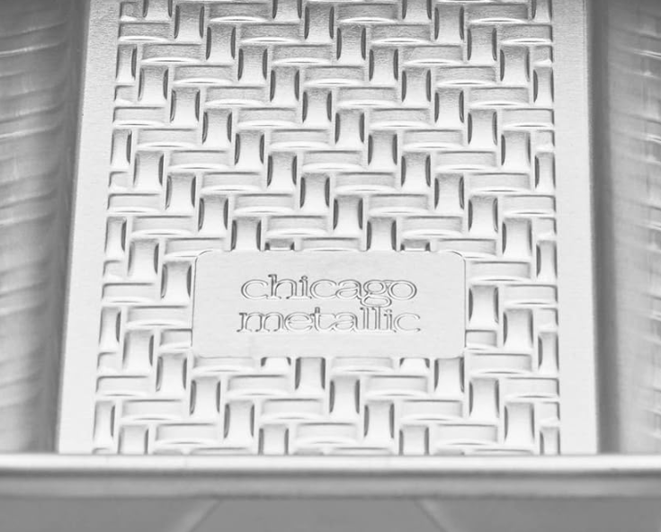 Silver 9" x 5" Chicago Metallic 1-pound loaf pan with a textured interior and smooth edges, shown on a white background.