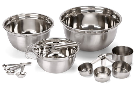 A set of stainless steel mixing bowls, measuring cups, and a whisk, arranged neatly for baking and cooking preparation.