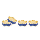 A set of four wavy, gold-toned napkin rings with a rich blue enamel finish.