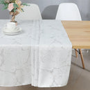 White and silver jacquard tablecloth spread over a medium dining table