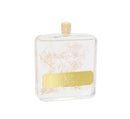 Elegant home fragrance diffuser in a clear glass bottle, showcasing preserved light pink and white flowers and accompanied by white diffuser sticks.

