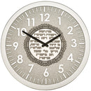 Silver-colored wall clock with easily readable numbers, showcasing a central ornamental plaque containing a meaningful Hebrew inscription for business prosperity.