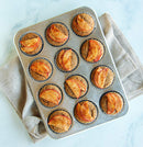 Apple Muffins in a Nordic Ware natural aluminum 12-cup muffin pan with evenly spaced round cavities on a white background.