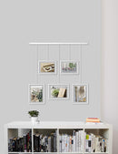 A contemporary white photo display featuring five square frames suspended from a horizontal bar by thin rods.