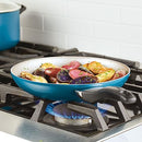 Farberware 15-Piece Aluminum Nonstick Cookware Set in a teal exterior with a light gray nonstick interior. The set includes various pots and pans with glass lids and black handles, along with a baking sheet and a set of black Prestige kitchen tools shown in an inset image.