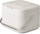 A ventilated, rectangular Joseph Joseph compost bin with the lid open, showing the built-in odor filter and a compostable liner inside.