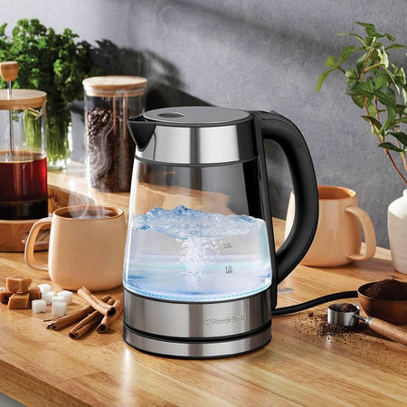  A sleek stainless steel electric kettle with a curved spout, sitting on a base with a power button.