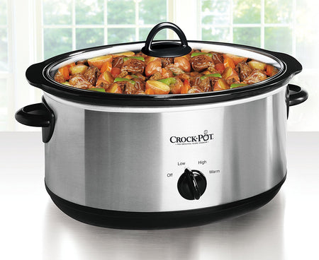 A modern slow cooker with a glass lid, showing a simmering stew, placed on a kitchen counter.