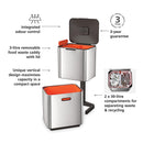 A two-tiered stainless steel trash and recycling bin with a black lid and base. The top compartment has a small, horizontal orange light on its front.