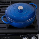 A 5-quart blue enameled cast iron braiser with matching lid, displayed against a stovetop