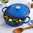 Blue enameled braiser on a stovetop, filled with braised meat and vegetables, ready to serve.