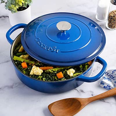 Blue enameled braiser on a stovetop, filled with braised meat and vegetables, ready to serve.