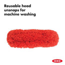 OXO Good Grips hand duster featuring a washable red microfiber head designed to attract and trap dust.