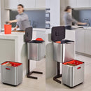 A two-tiered stainless steel trash and recycling bin with a black lid and base. The top compartment has a small, horizontal orange light on its front.