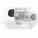 A white Starfrit electric pasta maker extruding long strands of fresh pasta. The machine has a clear top allowing a view of the dough inside. To the left, a white plate of cooked spaghetti with tomato sauce and shrimp is shown as a serving suggestion.