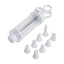 An image of a white and clear NORDPRO® cookie press and decorating set. The set includes a syringe-style plunger tool with finger loops and a clear tube. Also shown are eight interchangeable decorating tips of various shapes, all made of white plastic. 
