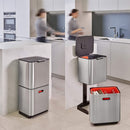 A two-tiered stainless steel trash and recycling bin with a black lid and base. The top compartment has a small, horizontal orange light on its front.